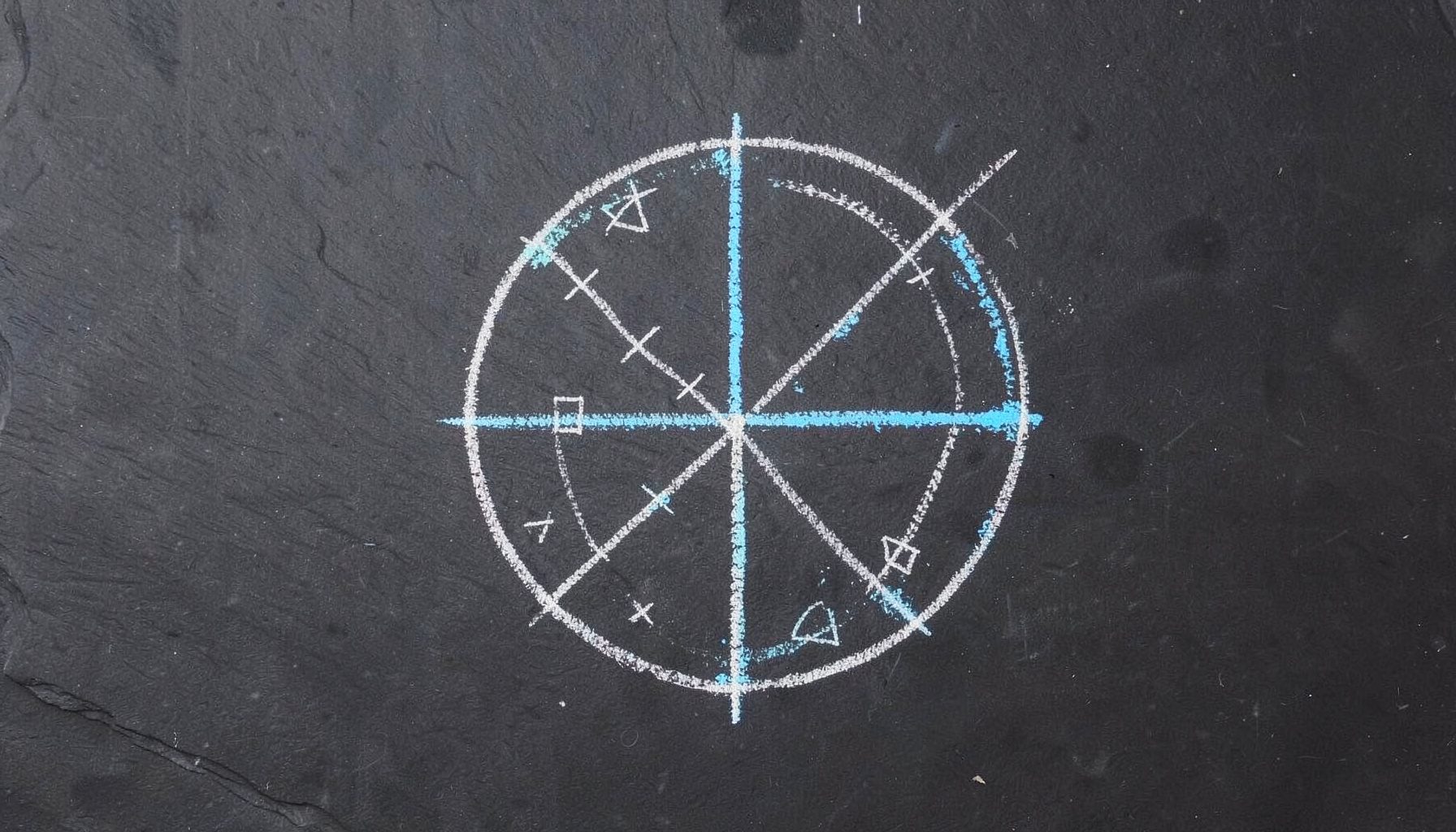 Chalk drawing on a dark slate board showing a simple globe outline with connecting lines and small geometric symbols