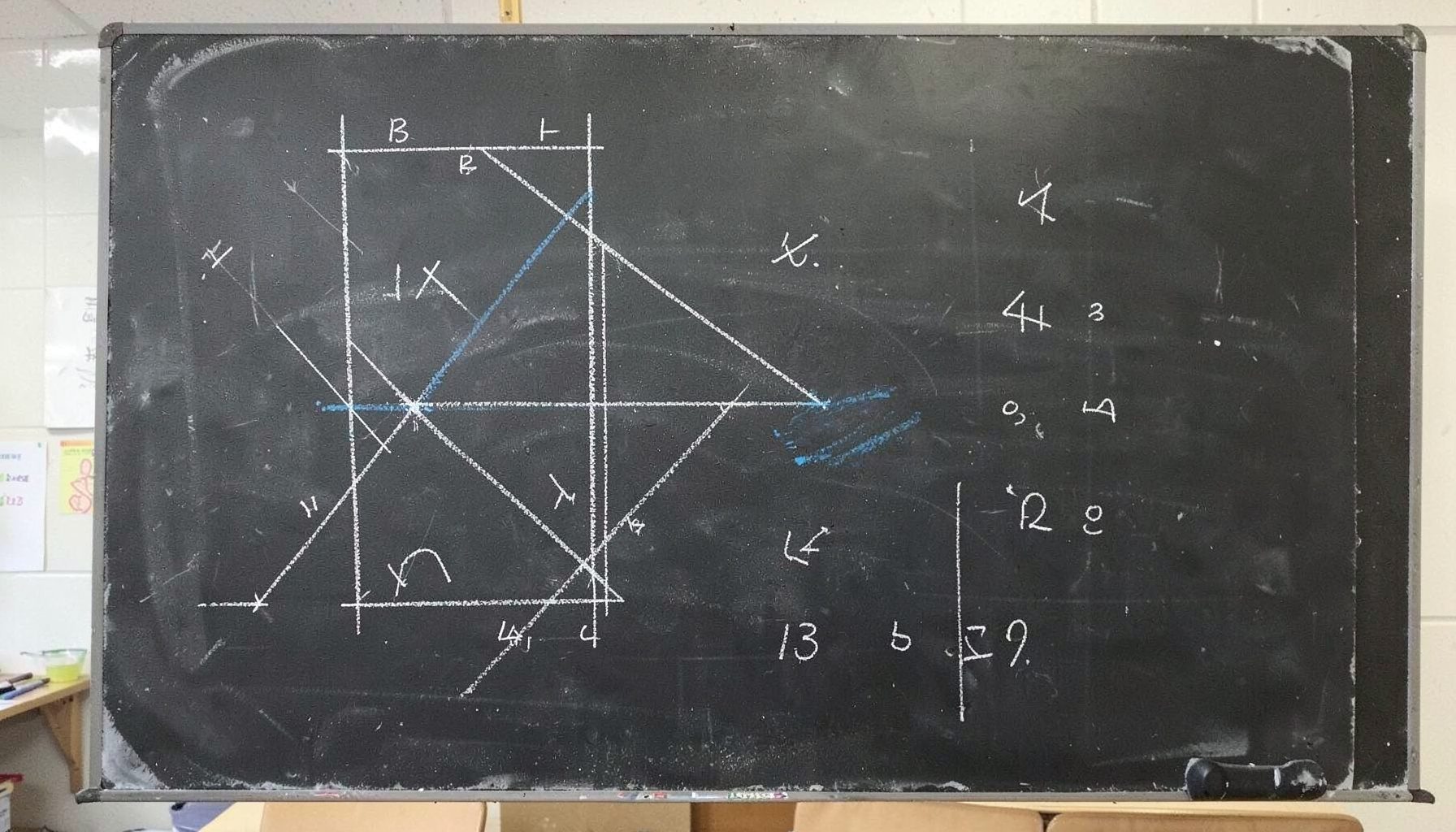 Chalk drawing on dark slate board with geometric survey diagrams and handwritten coordinates