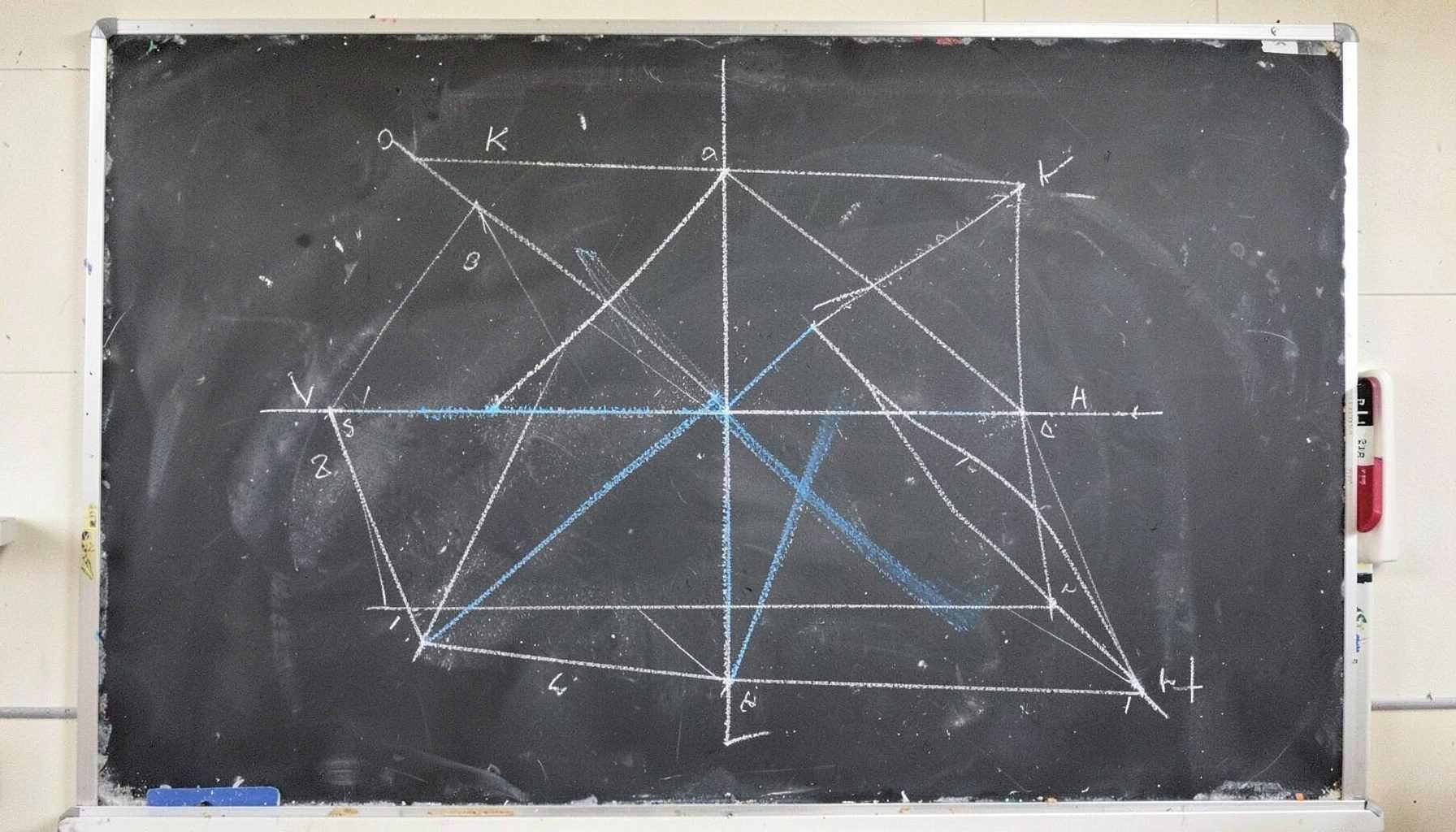 A chalk drawing on a dark slate board with triangulation points and angle measurements in white chalk